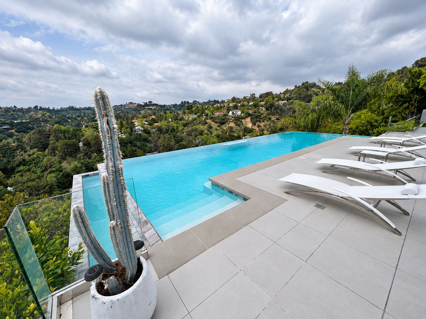 Infinity pool with hillside view and lounge chairs